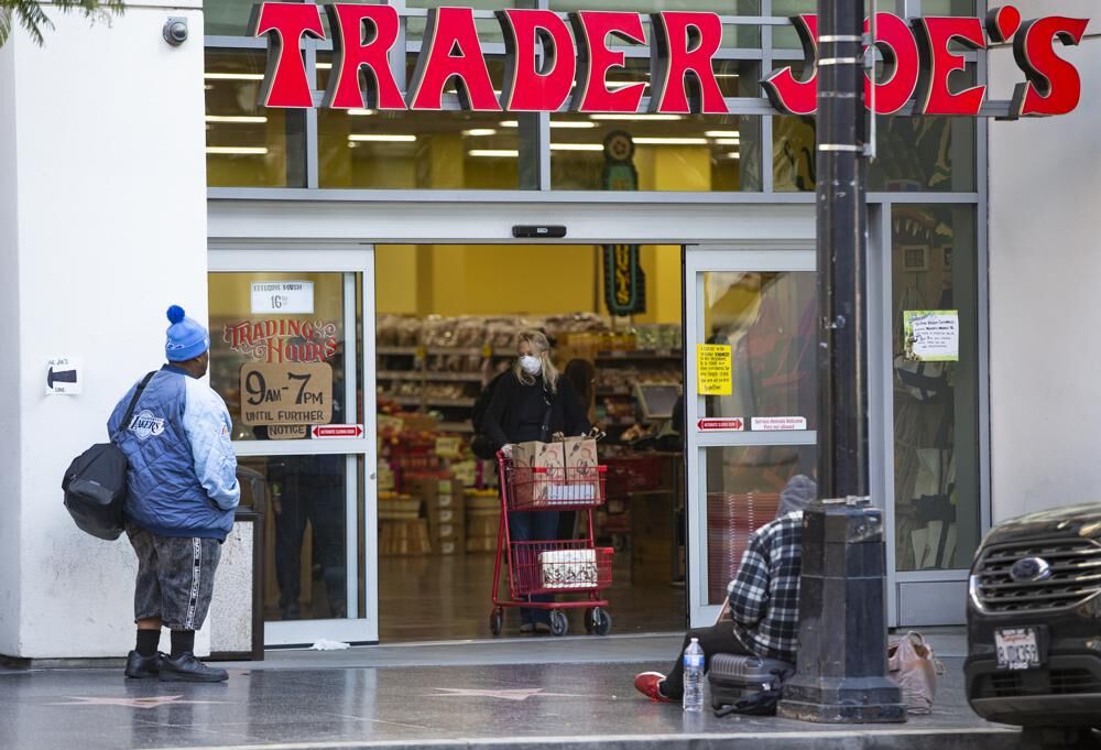 A person waits to enter a Trader Joe's grocery store.jpeg